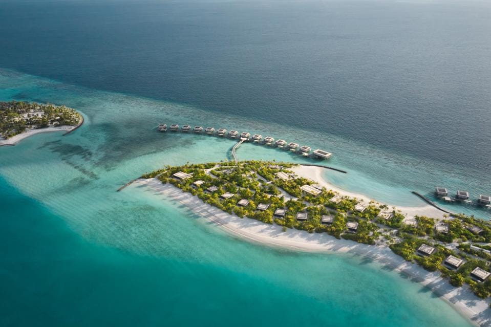 鸟瞰图显示了 Patina Maldives 度假村的水上平房和海滩别墅