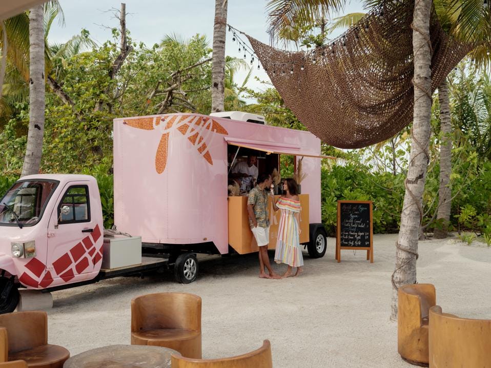 在帕蒂纳马尔代夫度假村，一对夫妇站在一辆出售 Gelado 的粉红色食品卡车前