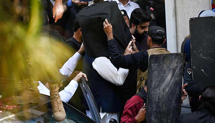 Security personnel use bullet proof shields to protect former prime minister Imran Khan (C) as he arrives at the high court in Islamabad on March 27, 2023. — AFP/File