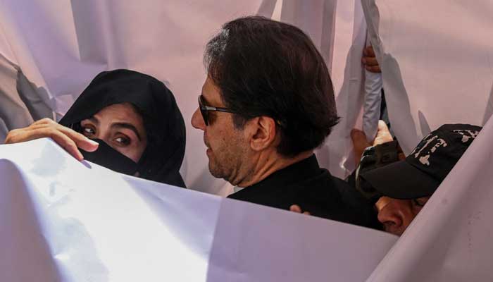 PTI Chairman Imran Khan with his wife Bushra Bibi arrive to appear at a high court in Lahore on May 15, 2023. — AFP