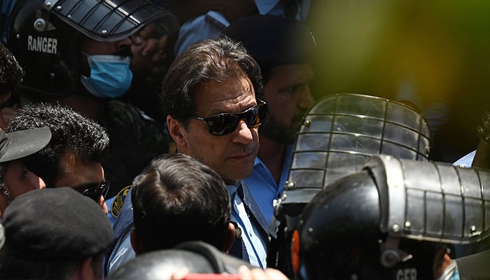 Police cammandos escort former prime minister Imran Khan (C) as he arrives at the high court in Islamabad on May 12, 2023. — AFP