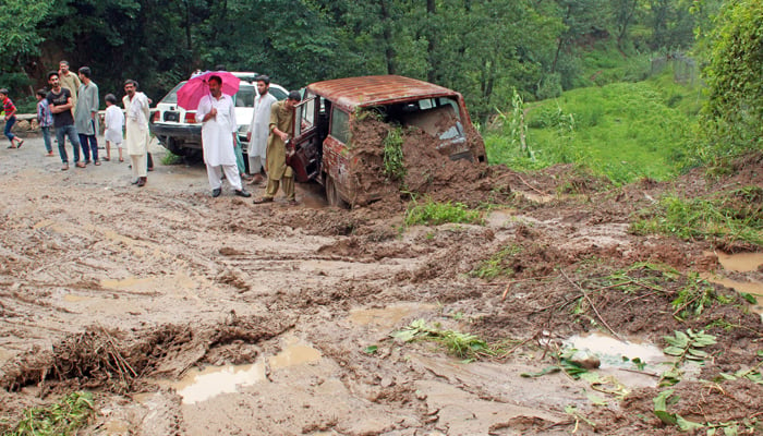 People standing near vehicles stuck in mud, as waiting for rescue heavy moon-soon rain in Abbottabad on July 7, 2023. — Online