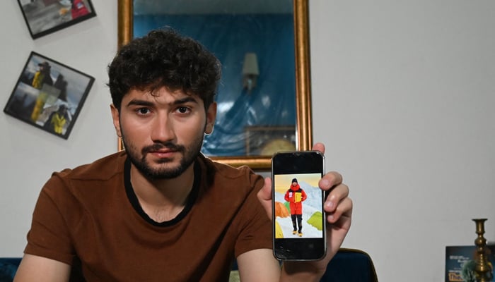 This picture taken on June 27, 2023 shows mountaineer Shehroze Kashif displaying his picture on a phone during one of his expeditions, after an interview with AFP inside his home in Lahore.