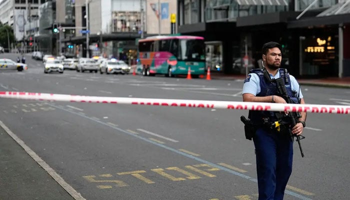 An armed New Zealand police officer stands at a roadblock in the central business district following a shooting in Auckland, New Zealand, Thursday morning.- Associated Press