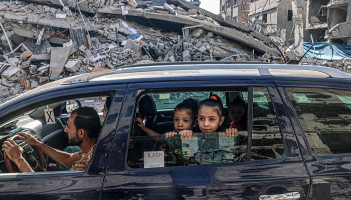 Palestinians drive amid the rubble of buildings destroyed in an Israeli air strike in Rafah, on the southern Gaza Strip on October 12, 2023. — AFP