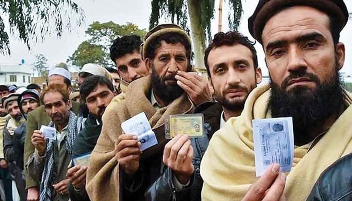 Afghan refugees seen showing their ID cards to the camera. — AFP/File