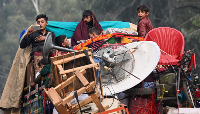 This photo taken on November 23, 2023, shows Afghan refugees on trucks leaving for Afghanistan after visiting the UNHCR Azakhel Voluntary Repatriation Centre in Nowshera. — AFP