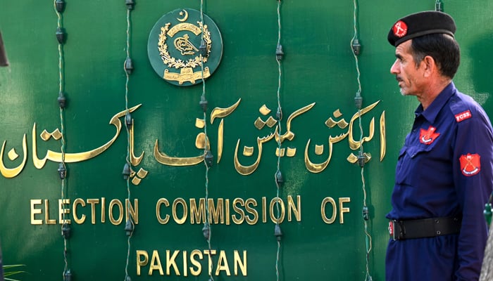 A security guard stands alongside the ECP sign board in Islamabad. — AFP/File