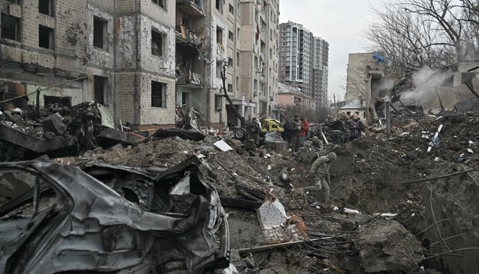 Experts examine a crater next to a multi-storey residential building destroyed by a missile attack in central Kyiv, on January 2, 2024. — AFP