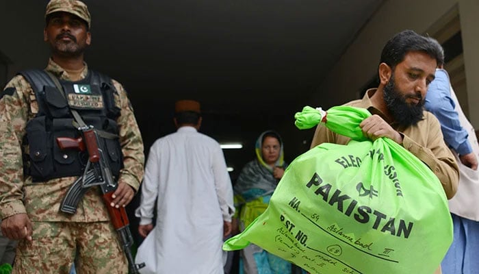 A soldier stands guard as an official carries election materials at a distribution centre in Islamabad on July 24, 2018. — AFP