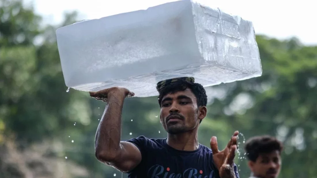 This undated image shows a man carrying a large block of ice on his head during a heatwave. Photo: Dhaka Tribune