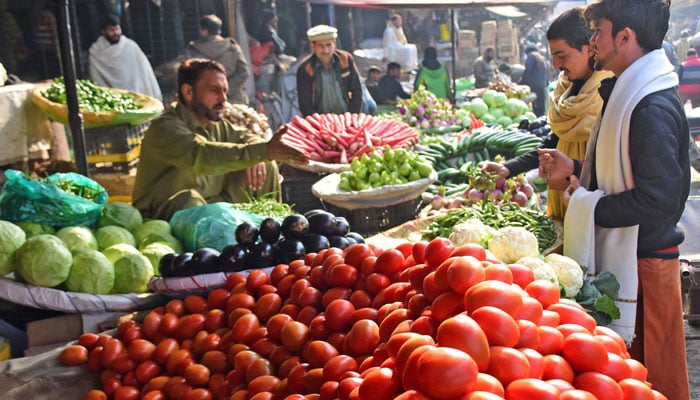 People buy vegetables from a vendor at a local market in Islamabad. — Online/File