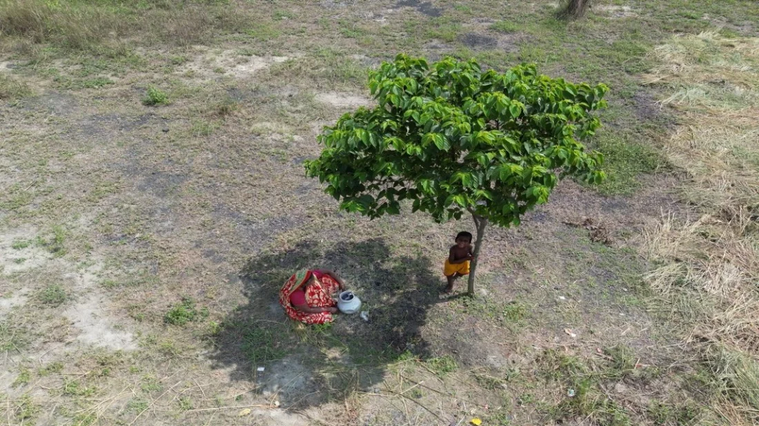 This undated image shows a woman and her child seeking refuge under a small tree from the scorching summer sun. Photo: Mahmud Hossain Opu/Dhaka Tribune
