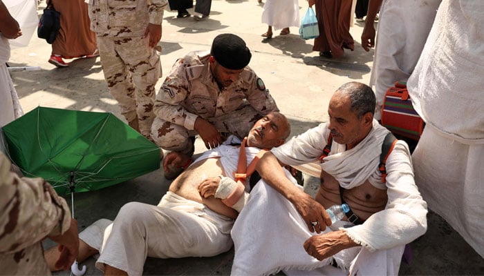 A pilgrim, affected by the scorching heat, is helped by a Saudi security forces member as pilgrims arrive to perform the stoning of the devil ritual during the annual Hajj pilgrimage in Mina on June 16, 2024. — AFP